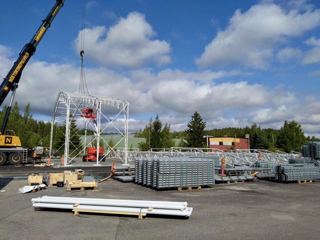 Hallin rakennusmateriaalit sekä nosturi konepajan pihalla.